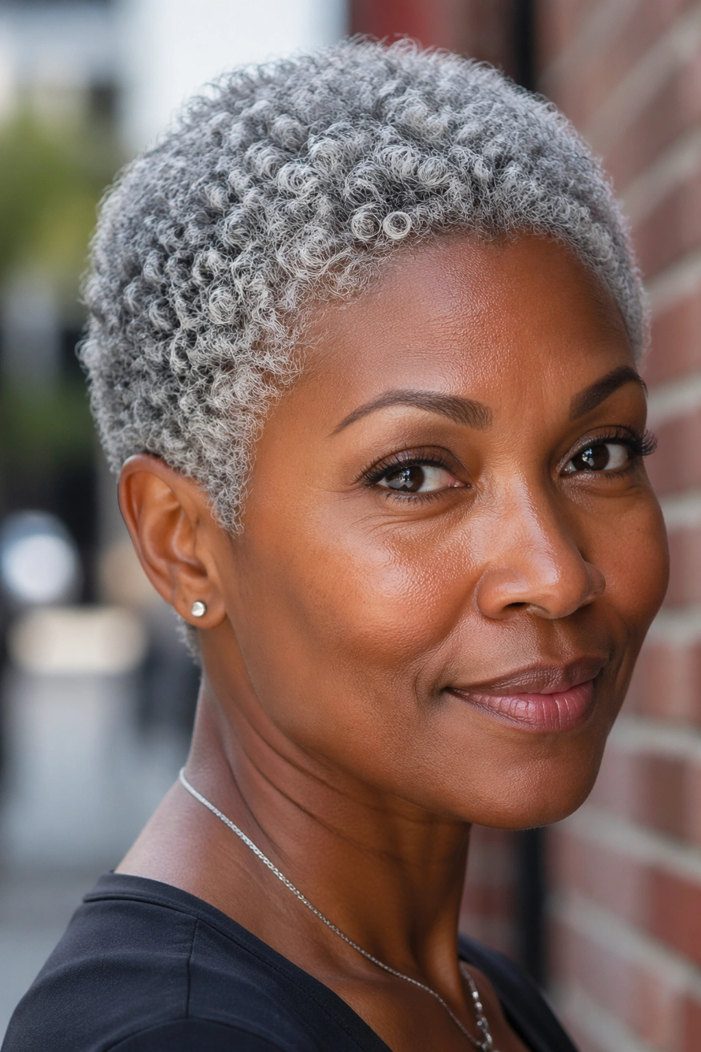 Close-up of a person with a grey TWA showing defined coils near the scalp