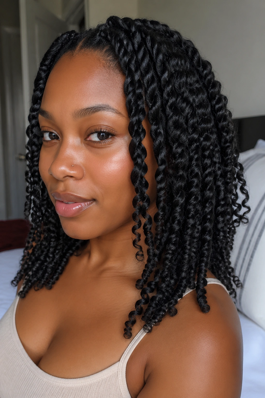Close-up of a real woman with two-strand twist-out curls in a softly lit bedroom