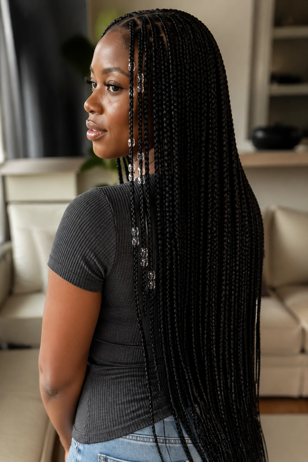 Close-up portrait of a real woman with waist-length knotless box braids and clear beads.