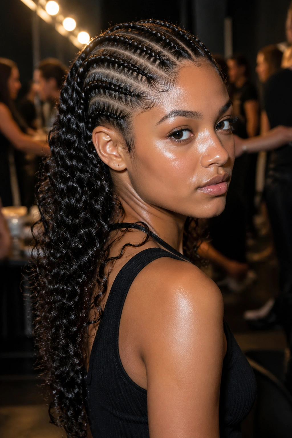 Real woman with glossy wet-look curls and cornrows backstage at a fashion shoot.