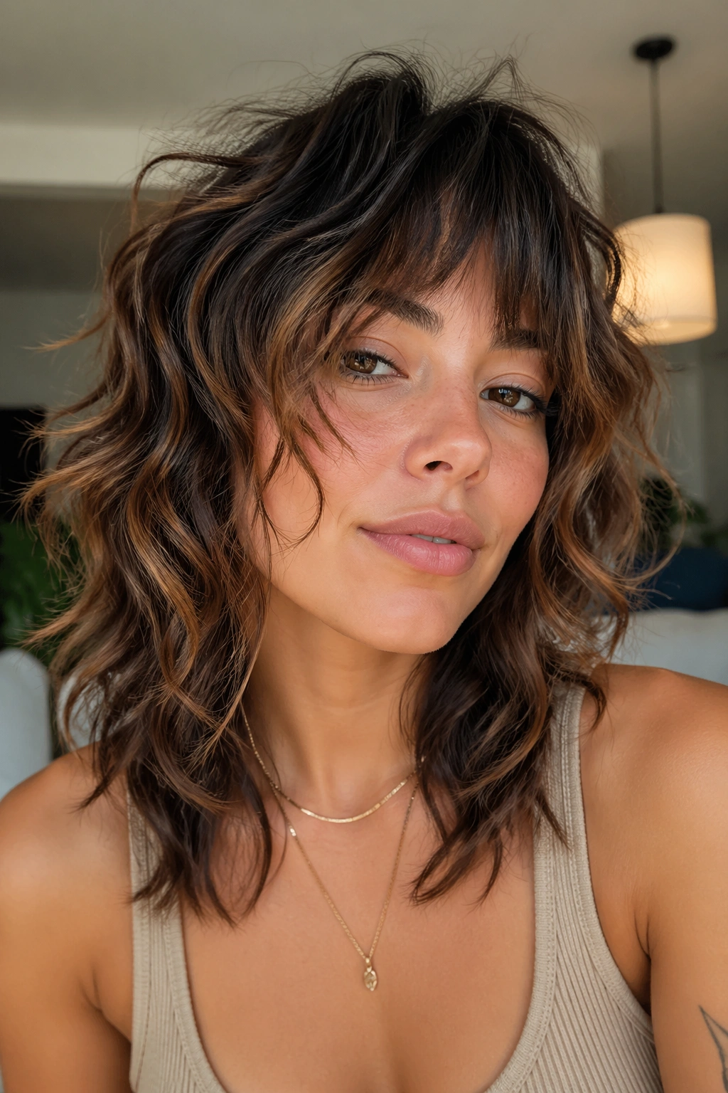 Close-up portrait of a woman with wolf-cut wavy shag in warm indoor light
