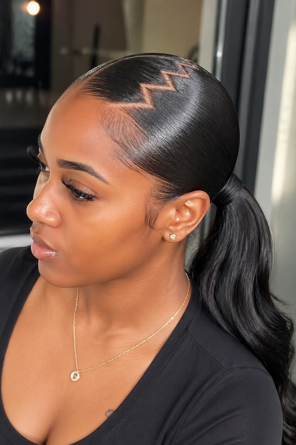 Close-up of a real woman with a sleek low pony and zigzag front part.
