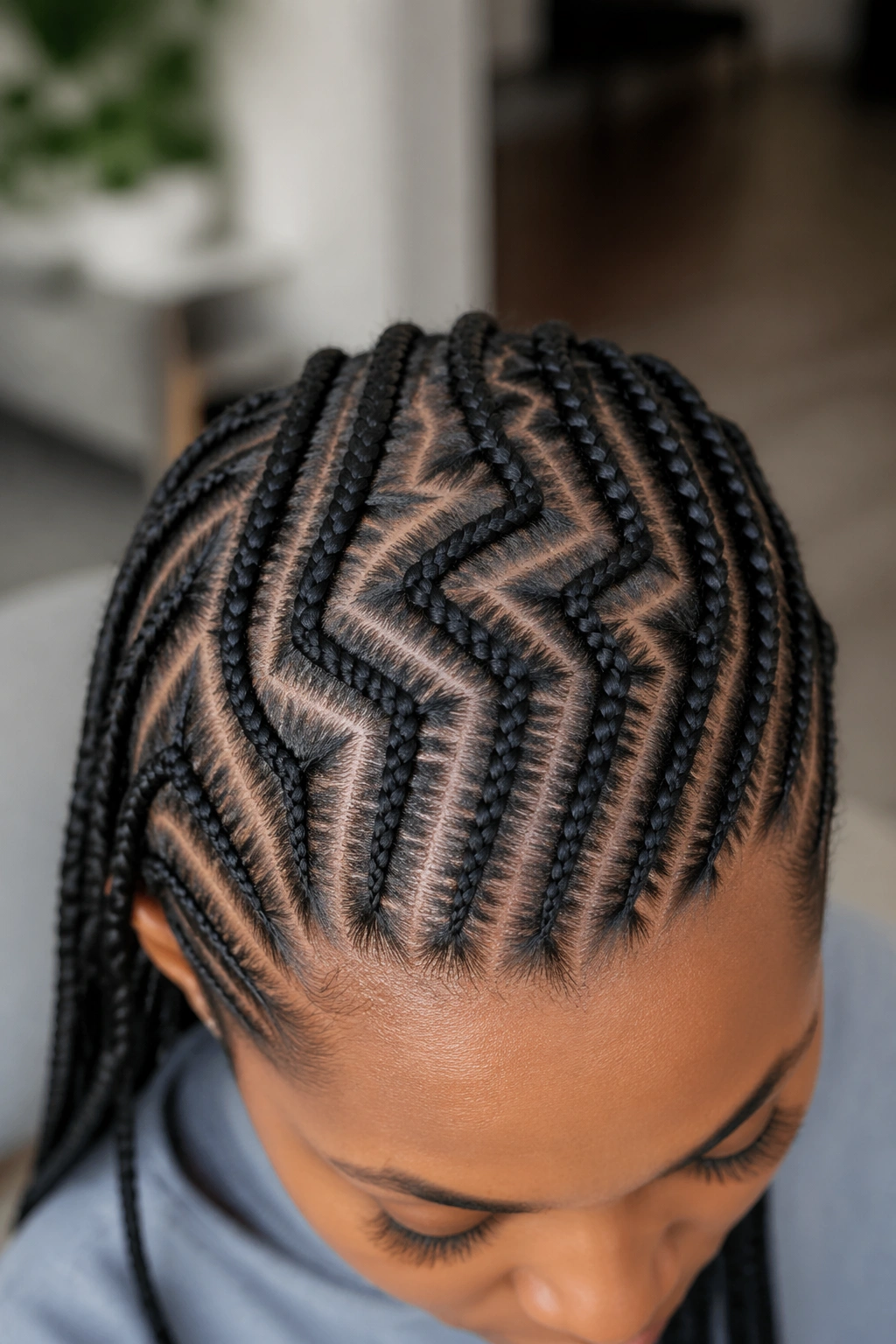 Close-up of real person's scalp showing zig-zag partings between small cornrows