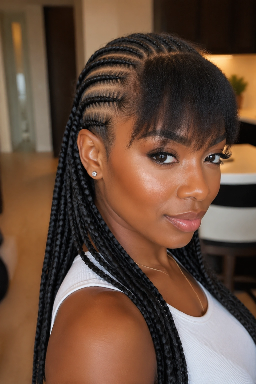 Real woman with bangs integrated into feed-in cornrows in a cozy interior