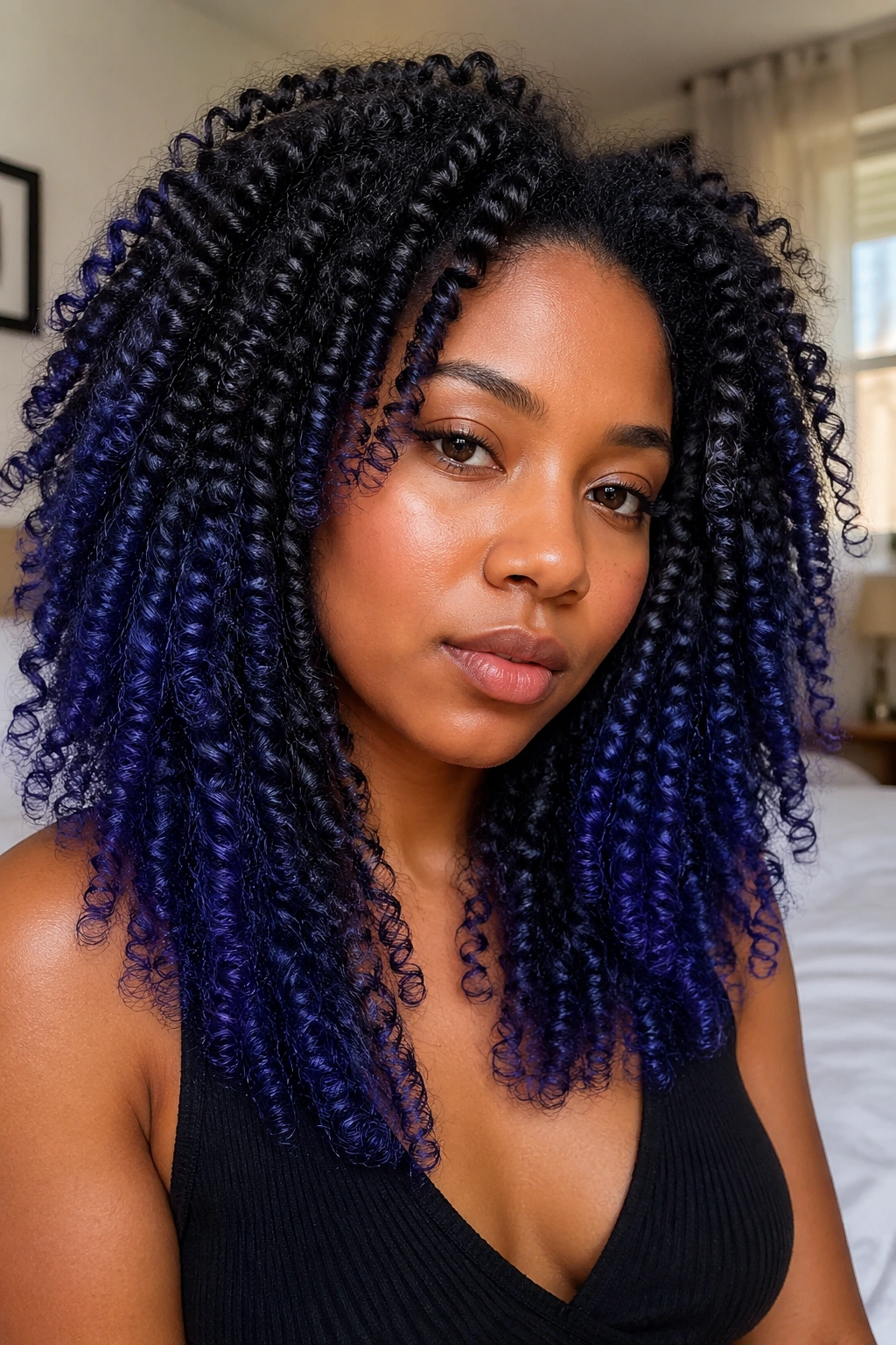 Close-up of a real person with 4B curls showing blue-violet ombre on ends under warm window light.