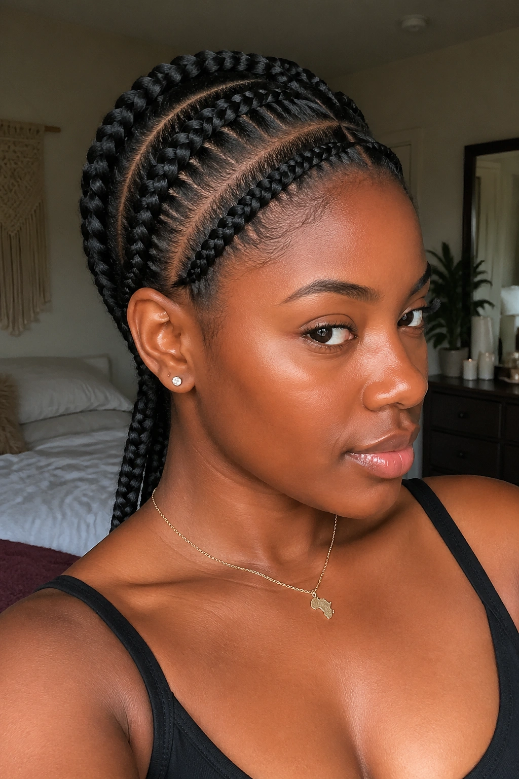 Close-up of a woman with four large cornrows running front to back in natural hair.