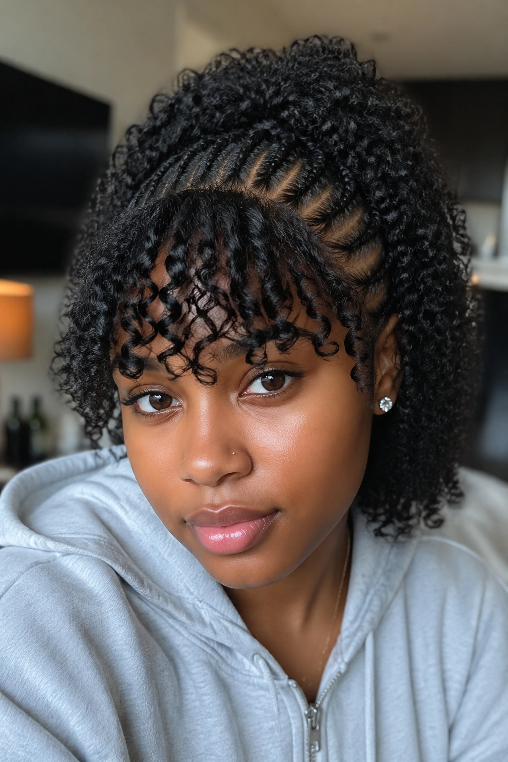 Portrait of woman with curly bangs created from half cornrows weave