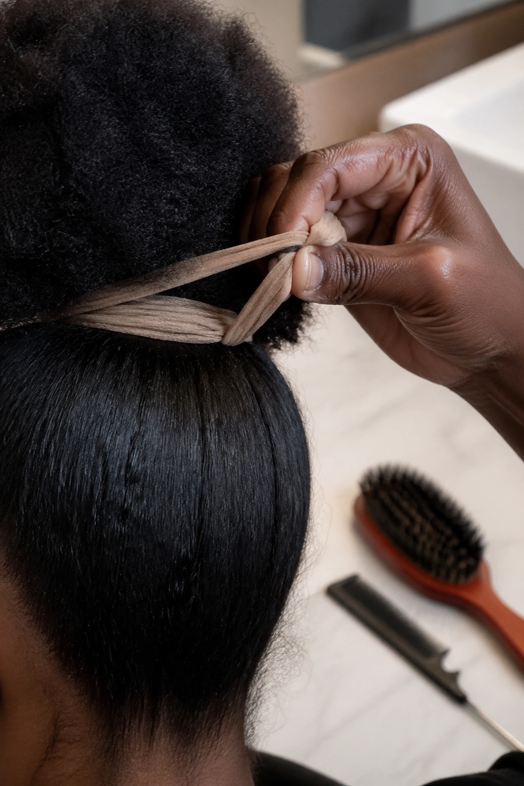 Hand tying nylon stocking puff headband with tools in soft focus on a bathroom counter