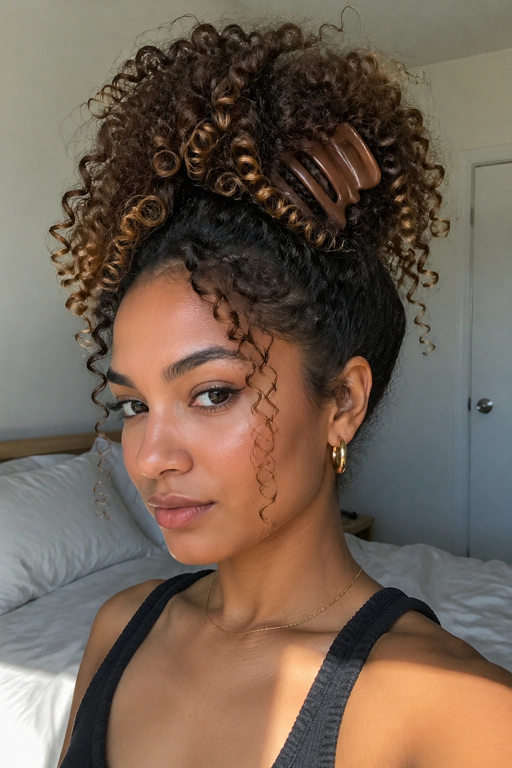 Close-up of a real woman with a high pineapple claw clip ponytail and curls fanning over the clip