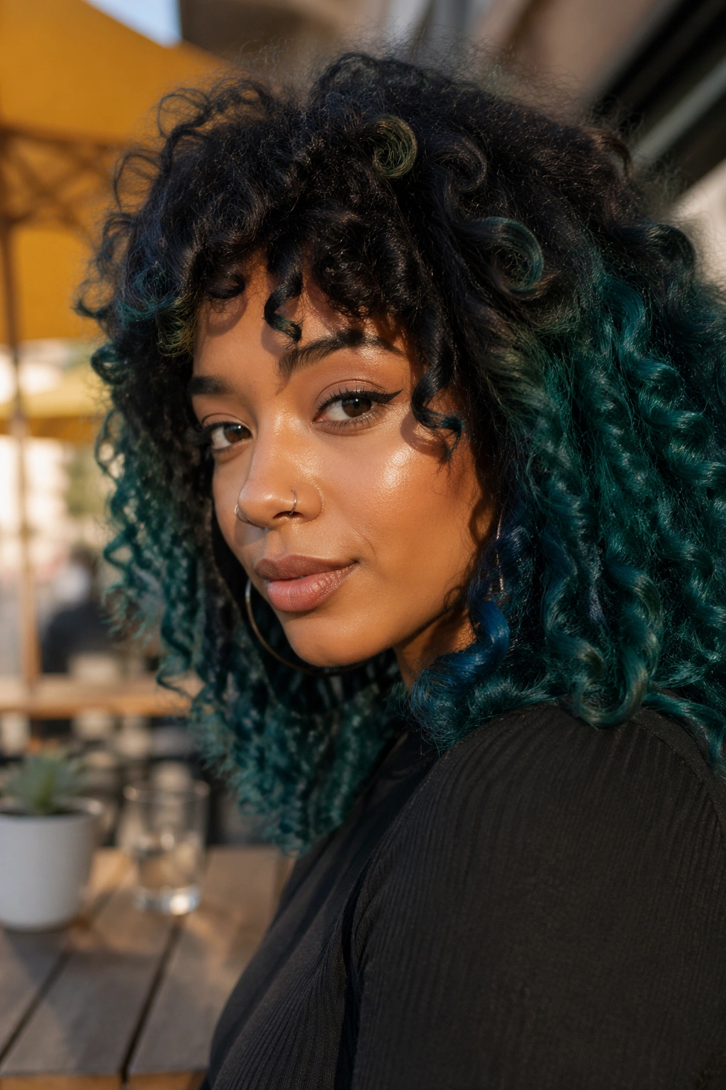 Close-up of a real woman's dark curls with teal balayage outdoors