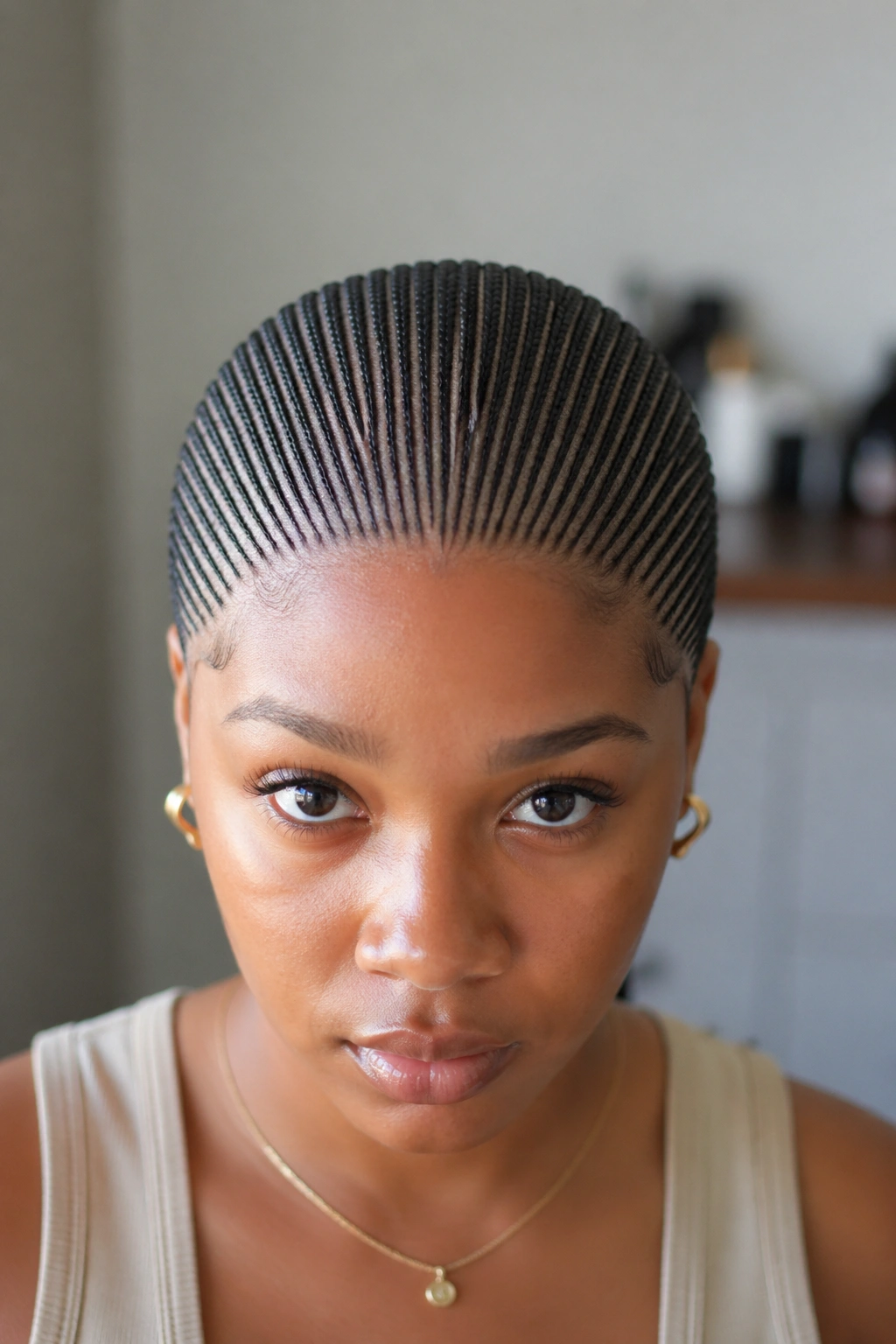 Front portrait of a real woman with thirty small cornrows across the scalp.