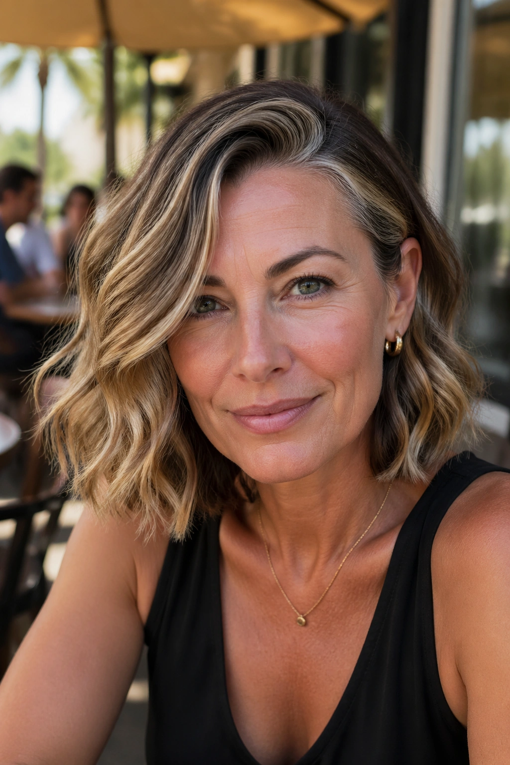 Real woman with wavy lob and side part outdoors on a sunny terrace