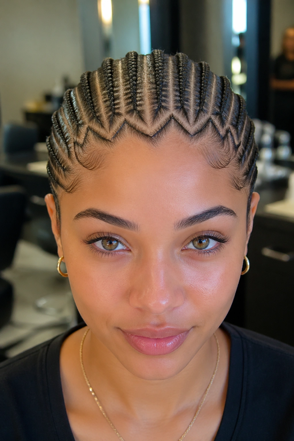 Front close-up of a real person with twelve cornrows and a zigzag hairline.